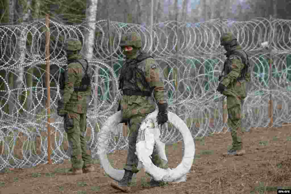 Un soldat polonez transportă colaci de sârmă ghimpată în timpul primei etape de construcție a gardului. Există temeri că Moscova ar putea orchestra un aflux de migranți ilegali în UE, similar cu ceea ce s-a întâmplat la granița cu Belarus, în 2021, când Minskul ar fi „direcționat” mii de migranți spre teritoriul polonez, leton, lituanian și eston. 