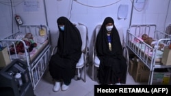 Nënat qëndrojnë pranë fëmijëve të tyre që trajtohen në një spital në Herat të Afganistanit. 