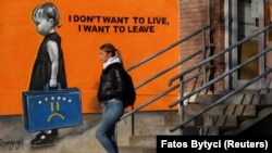 Një qytetare në Prishtinë kalon pranë një grafiti ku shkruan "Nuk dua të jetoj, dua të largohem". 