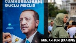 Türkiýäniň prezidenti Rejep Taýýip Erdoganyň suratynyň deňinden geçip barýan bir aýal, 19-njy iýun 2018, Stambul
