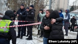 Zyrtarë policorë dhe disa banorë të mbledhur afër një zone të sulmuar në Ukrainë më 23 janar.
