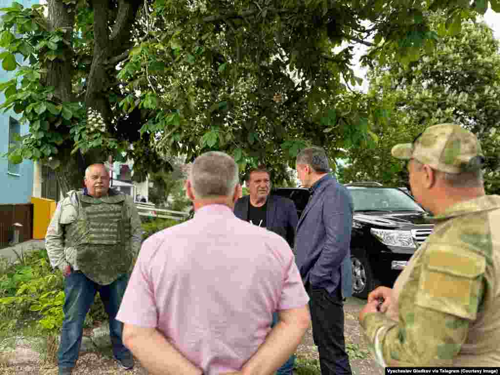 A man wears an armored vest as Belgorod Governor Vyacheslav Gladkov (in blue jacket) meets residents near where fighting took place. Leaders of the anti-Kremlin Russian militants say cross-border raids are intended to inspire Russians to rise up against their government.