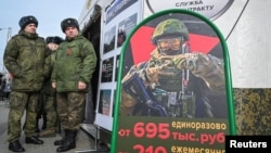 Soldații ruși stau lângă un centru mobil de recrutare cu un panou care conține informații despre plăți în Rostov-pe-Don, Rusia.