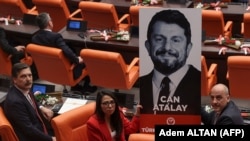 Képviselőtársak a bebörtönzött Can Atalay portréjával az új török parlament eskütételén Ankarában, 2023. június 2-án
