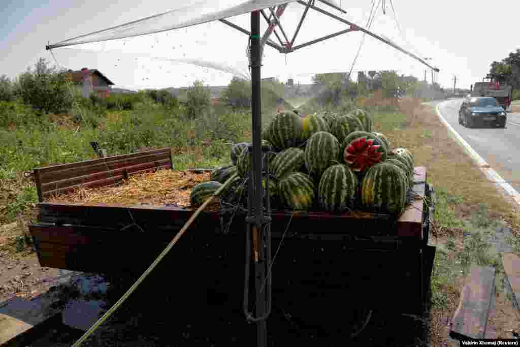 Në pritje të blerësve, shitësit e shalqirit në ambiente të hapura kujdesen që t'i mbajnë këto fruta sa më të freskëta nën një rrjedhë të vazhdueshme uji. 