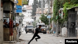 Një palestinez duke vrapuar në rrugë gjatë përplasjeve me trupat izraelite në Bregun e pushtuar Perëndimor, 13 qershor 2023.