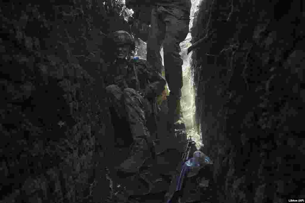 Një ushtar ukrainas duke u fshehur në një llogore pas bombardimeve ruse. 