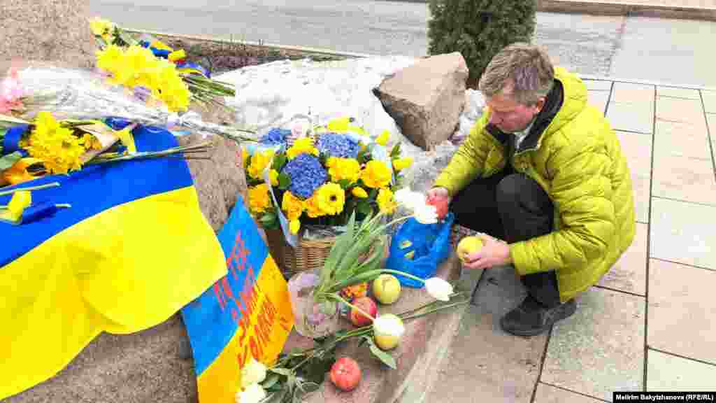 Украин ақыны Тарас Шевченконың ескерткіші алдына алма қойып жатқан адам. Ресей Украинаға басқыншылық соғыс ашқанына бір жыл толған күні осы ескерткішке адамдар гүл, алма, Украина туы мен "Соғыс тоқтасын!" деген жазуы бар плакаттар қойды.