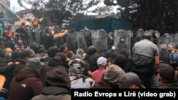 Ekipet e mediave shihen majtas gjatë një prej përleshjeve të protestuesve me pjesëtarët e KFOR-it në Zveçan, 29 maj 2023.
