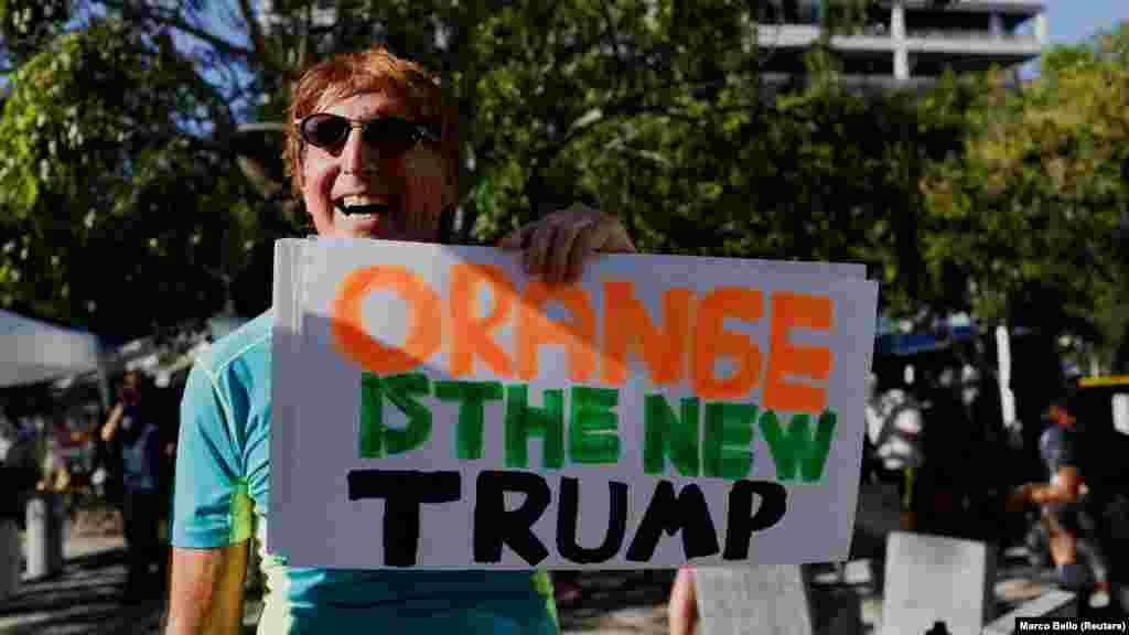 A narancs az új Trump – áll az egyik demonstráló tábláján, utalva a Donald Trump megválasztását követően elterjedt, egy népszerű sorozat címéből kölcsönzött mondásra, miszerint a narancsszínű bőréről ismert Trump váltja a fekete Obamát
