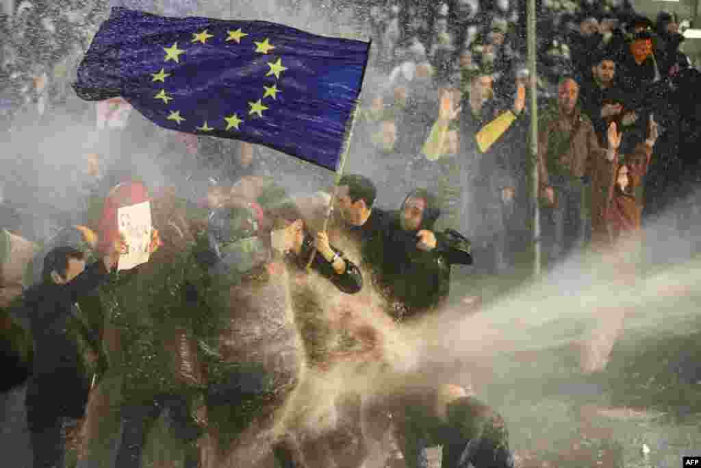 Protestatari care țin un steag al UE sunt loviți de jetul unui tun cu apă în timpul protestului din 7 martie. Șeful politicii externe a UE a calificat proiectul de lege drept o „evoluție foarte proastă” pentru această țară caucaziană.