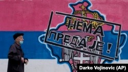 Një burrë kalon pranë grafiteve që përshkruajnë një hartë të Kosovës dhe stemën serbe dhe një flamur që lexon: "S'ka dorëzim!", Beograd, 26 prill 2023.