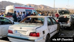 Disa njerëz qëndrojnë pranë makinave të shkatërruara pas një shpërthimi në Kerman. Iran, 3 janar 2024. 