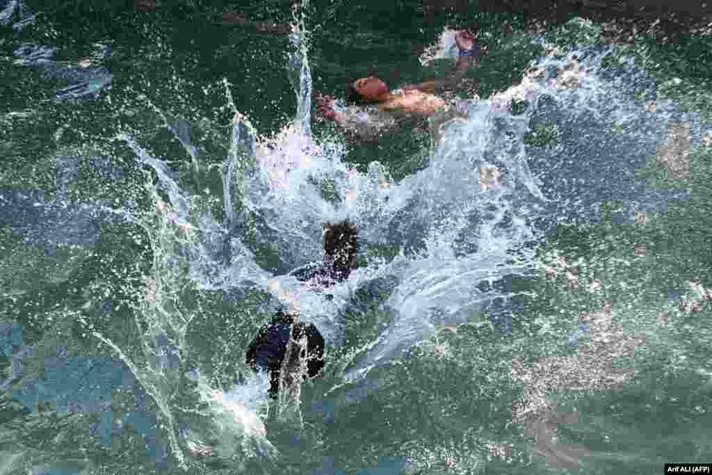 Băieți ce se răcoresc într-o piscină într-o zi toridă la Lahore, Pakistan.