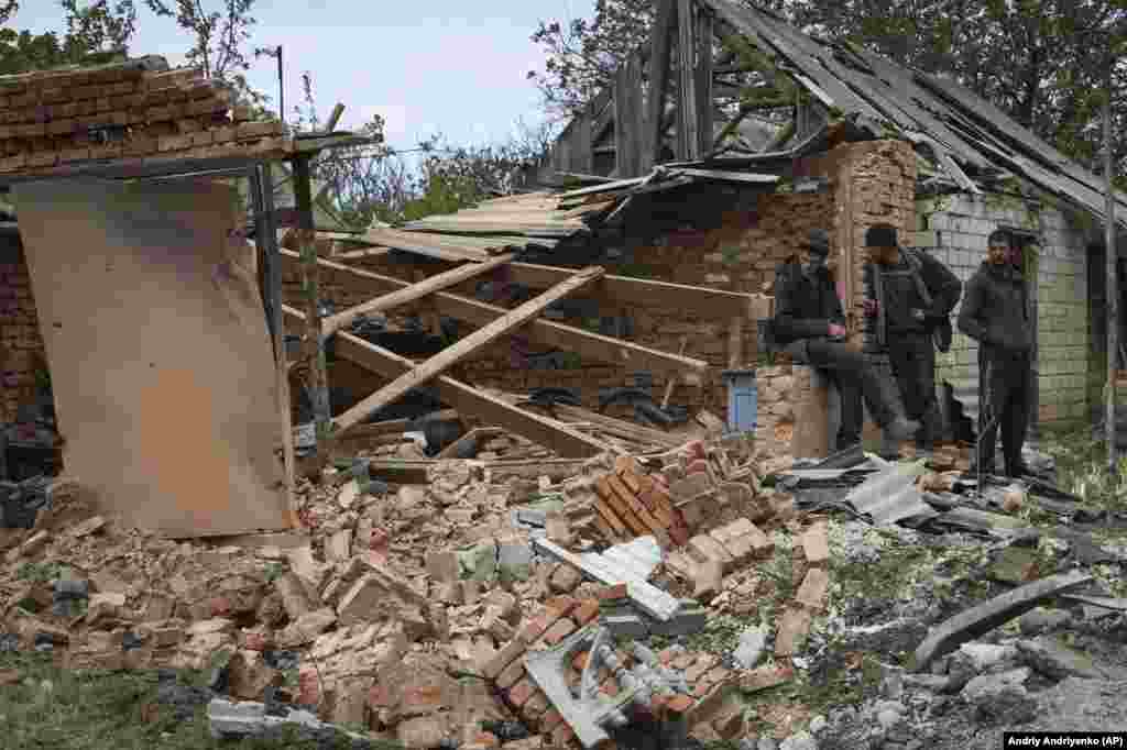 Locuitorii se află lângă o clădire avariată de bombardamentele rusești în Komyshevakha, regiunea Zaporizhzhya, la 8 mai.