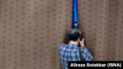 یک خبرنگار در حال عکاسی از ابراهیم رئیسی در یک نشست رسمی در تهران، مرداد ۱۴۰۲