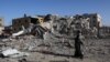 Një palestineze duke kaluar pranë një ndërtese të shkatërruar në Han Junis, në jug të Rripit të Gazës. 24 nëntor 2023.
