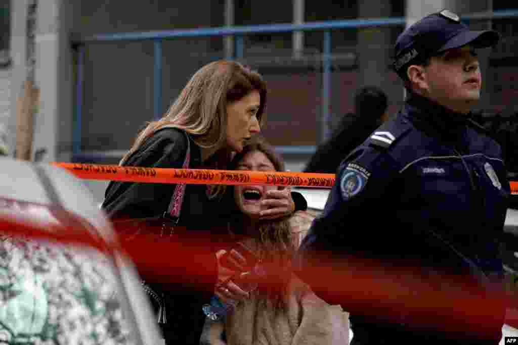 Një prind që përpiqet ta qetësojë një fëmijë pas sulmit në shkollë në Beograd, më 3 maj 2023.