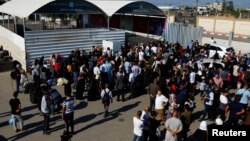 Palestinieni cu dublă cetățenie se adună în fața punctului de trecere a frontierei Rafah cu Egiptul, în sudul Fâșiei Gaza, 16 octombrie 2023.