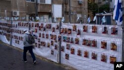  Israel - Un bărbat trece pe lângă un gard cu fotografii cu ostatici, în mare parte civili israelieni, care au fost răpiți în timpul atacului fără precedent al Hamas din 7 octombrie asupra Israelului, în Ramat Gan, Israel, miercuri, 22 noiembrie 2023.