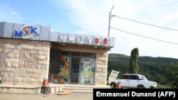 Nagorno-Karabakh - An abandoned vehicle is parked in front of a closed shop in Stepanakert during an Azeri government organized media trip, October 2, 2023. 