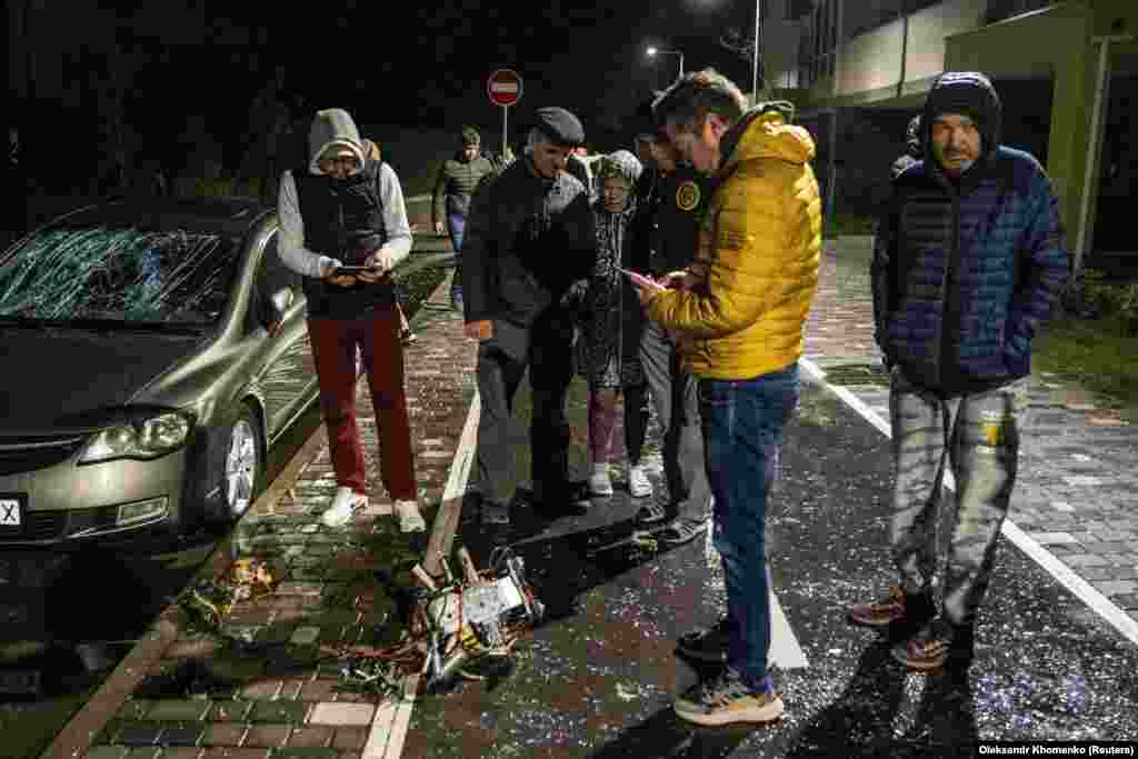 Locuitorii din Kiev inspectează o parte dintr-o dronă sinucigaș. Autoritățile locale consideră că este o dronă Shahed-131/136 de fabricație iraniană - care a fost doborâtă în timpul atacului efectuat de ruși peste noapte.