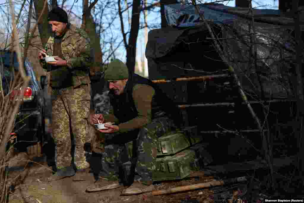 Soldați din Brigada a 10-a de vânători de munte a armatei ucrainene iau prânzul în timpul unei pauze lângă buncărul lor de pe frontul din regiunea Bahmut, la 7 decembrie. 