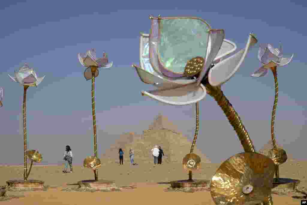 Vizitorët kalojnë pranë veprës së artit "Pulse and Bloom" të artistit indian Shilo Shiv Suleman gjatë ekspozitës së artit bashkëkohor "Forever Is Now" në vendin historik te Piramidat e Gizës, në periferi të Kajros, Egjipt, të enjten, 24 tetor.