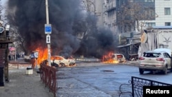 Cars burn on a street after Russian missile strikes on the Ukrainian port city of Kherson on December 24.