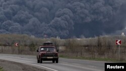 Цивільне авто на тлі пожежі на нафтопереробному заводі в Лисичанську, яка почалась через обстріл. 16 квітня