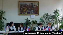 Members of an electoral commission wait for voters at a polling station in the Donetsk region during a referendum on the territory joining the Russian federation, which has been dismissed by Ukraine, Western governments, and the United Nations because the vote is illegal under international law.