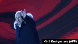 Președintele Vladimir Putin salută mulșimea la o demonstrație/concert care a marcat patru ani de la anexarea Crimeii, Piața Manejnaia, Moscova, 18 martie 2018.