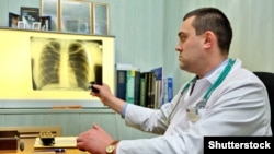 Дарыгер учук оорулуу бейтаптын өпкөсүнүн флюрографиясын карап жатат.