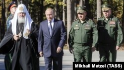 Kirill orosz ortodox pátriárka Vlagyimir Putyin orosz elnök, Szergej Sojgu hadügyminiszter és Valerij Geraszimov vezérkari főnök társaságában indul megáldani Moszkvában az Orosz Fegyveres Erők főtemplomát az alapkőletételkor, 2018. szeptember 19-én