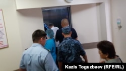 В глубине лифта кардиологического центра в Алматы — один из конвойных, ближе (в белой майке) фигурант дела о «пропаганде терроризма» Жулдызбек Таурбеков, еще ближе - человек в штатском, руководивший действиями конвойных, еще ближе — еще один конвойный. Алматы, 6 июля 2019 года.