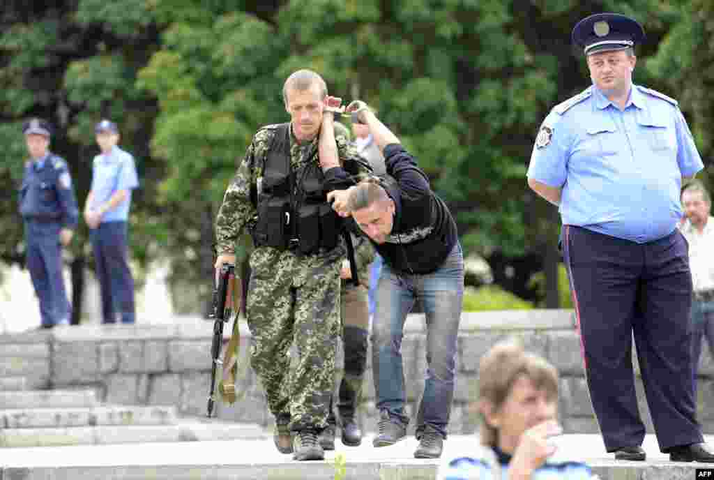 Проросійський бойовик затримує чоловіка, підозрюваного у шпигунстві для України, під час церемонії принесення присяги на вірність так званій «ДНР», Донецьк, 21 червня 2014 року
