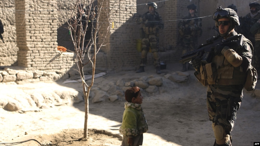A child watches as French soldiers search houses in Kapisa Province days after the journalists were kidnapped.