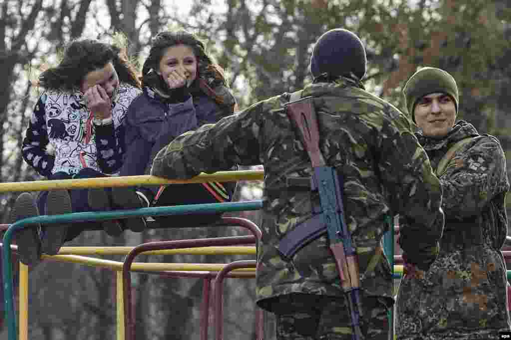 Молоді українські солдати жартують з дівчатами на спортмаданчику. Місто Ізюм, 16 березня 2015 року 