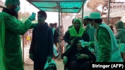 Pakistani health officials check the body temperature of Afghan nationals at the Torkham border crossing earlier in March.