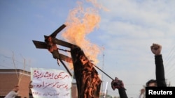 A student holds a burning effigy depicting Raymond Davis.