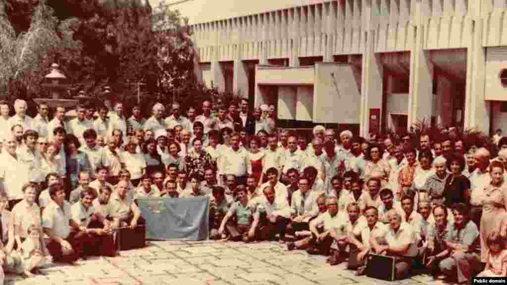1991 senesi iyün ayı. Bular Aqmescitteki ekinci Qurultaynıñ iştirakçileri ve musafirleri. Eki Qurultay arasında 70 yıldan çoq vaqıt keçti. Sürgünlikten Vatanına qaytıp kelgen qırımtatarlarnıñ qollarında 20-nci asırnıñ başında tasdıqlanğa Milliy bayraq 
