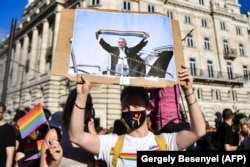 Një protestues duke e mbajtur një pankartë që e shfaq kryeministrin e Hungarisë, Viktor Orban, duke e mbajtur një shall me ngjyrat e ylberit, pranë ndërtesës së Parlamentit në Budapest, gjatë një proteste më 14 qershor 2021.