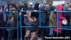 Migrants stand in line to get hot food at a logistics center along the Belarus-Poland border near Hrodno, Belarus, on December 21.