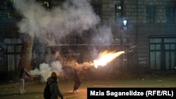 Një protestues hedh një fishekzjarr mes përleshjeve me policinë në qendër të Tbilisit, në orët e para të 4 dhjetorit.