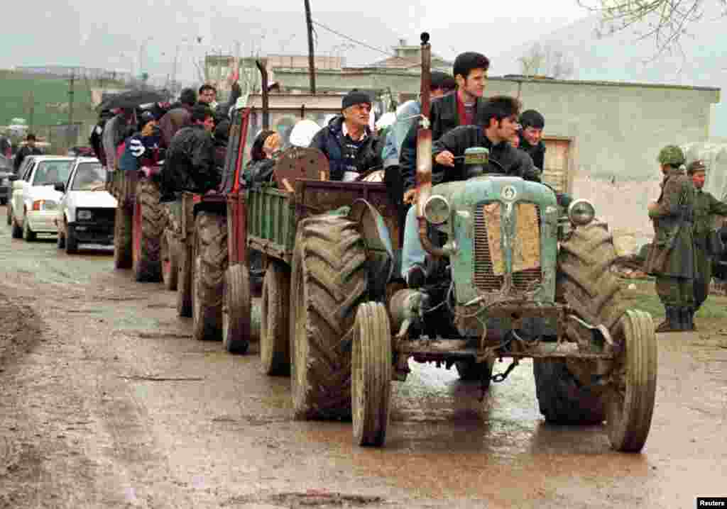 Traktorë të mbushur me refugjatë shqiptarë duke kaluar në Shqipëri, të cilët janë larguar me dhunë nga shtëpitë e tyre nga policë dhe ushtarë serbë, 28 mars 1999. Arben Celi/Reuters. 