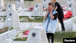 Një djalosh duke u lutur para varrezave të personave të vrarë në Reçak më 1999.
