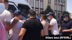 Азаматтық киім киген 40 шақты адам Шымкент әкімдігі алдында белсенділерді күшпен газельге отырғызып жатыр. 1 шілде 2021 жыл.