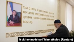 Президент Шавкат Мирзияевтің суреті ілініп тұрған сайлау учаскесінде дауыс беріп тұрған тұрғын.