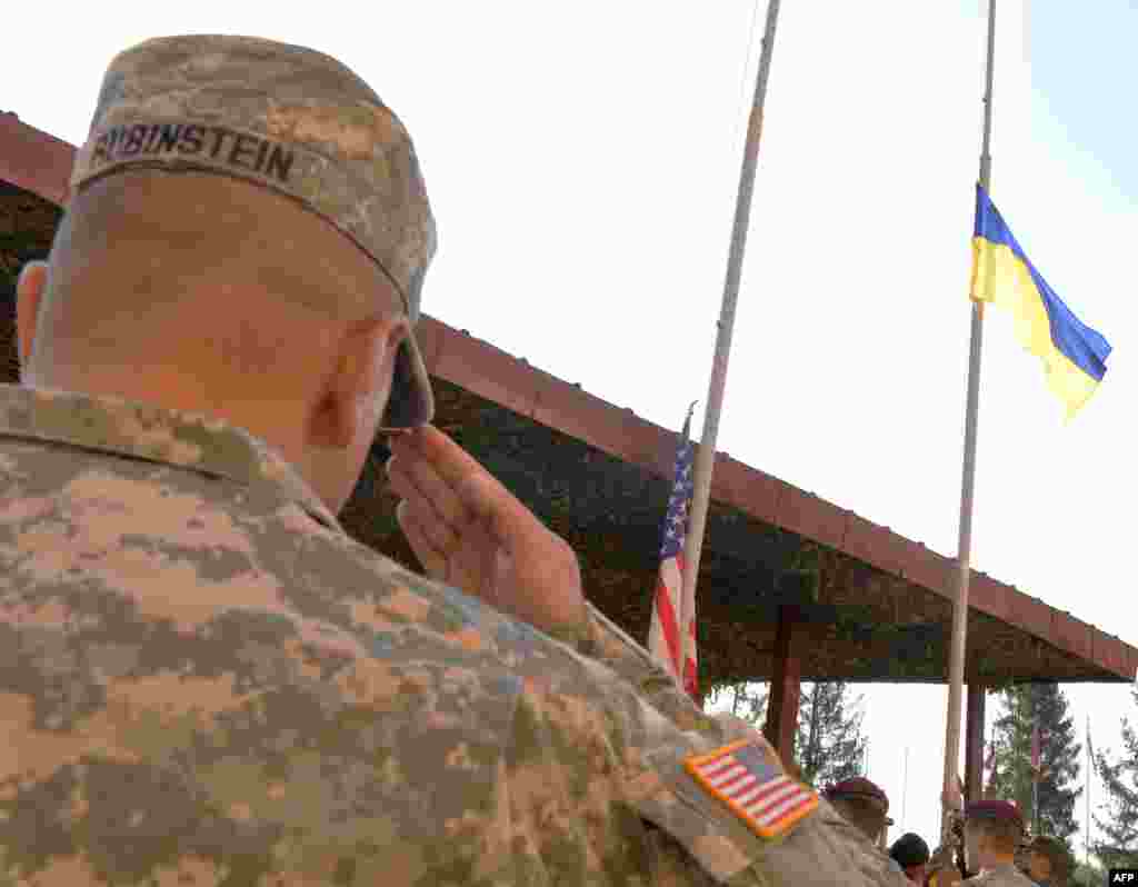Военнослужащий США отдает честь флагу Украины во время церемонии открытия учений "Быстрый трезубец-2014".