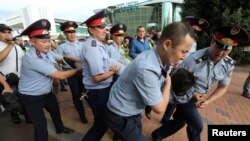 Полиция наразылық өтуі тиіс маңнан өтіп бара жатқан адамды ұстап әкетіп барады. Алматы, 6 шілде 019 жыл.